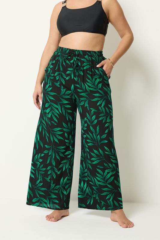 YOURS Plus Size Black & Green Leaf Print Crinkle Beachwear Wide Leg Trousers | Yours Clothing 1